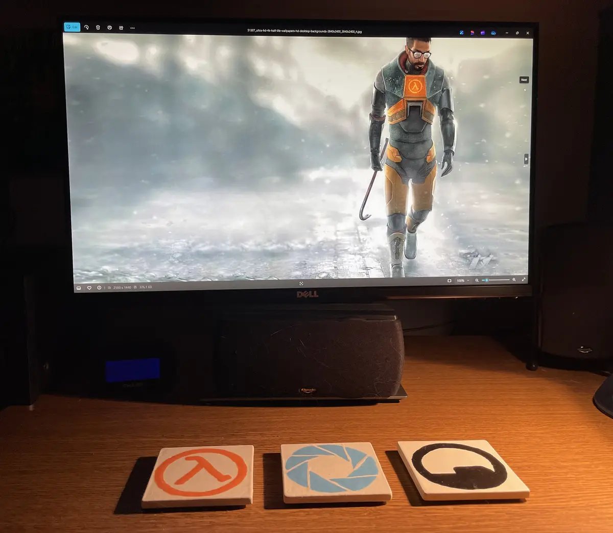 A computer monitor displays a Half-Life wallpaper featuring a character in a grey and orange suit walking through a snowy…