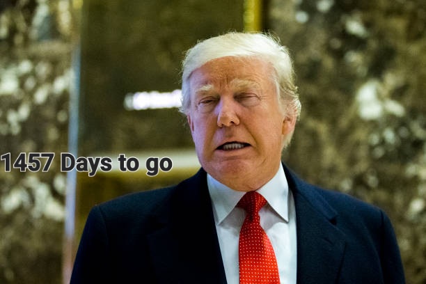 A close-up photo of Donald Trump wearing a dark suit and red tie, looking slightly upward with a serious expression. Text…