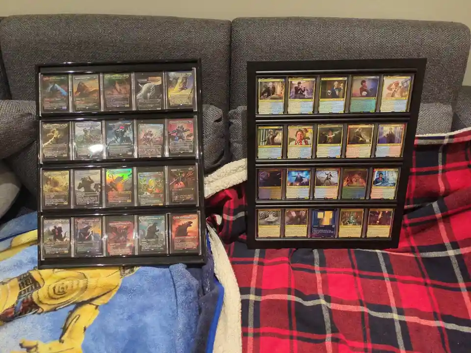 Two black-framed display cases sit on a couch, each holding multiple Magic: The Gathering cards. The left case contains…
