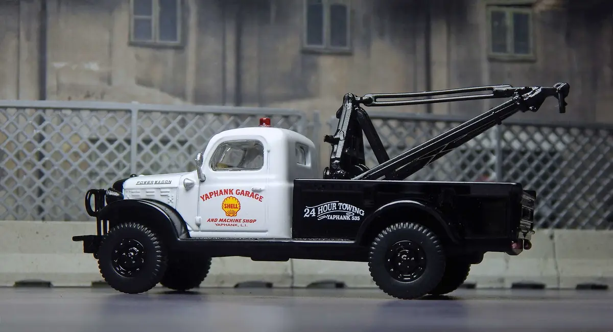 A toy model of a white and black tow truck with a large black crane arm, labeled 'YAPHANK GARAGE AND MACHINE SHOP' and '24…