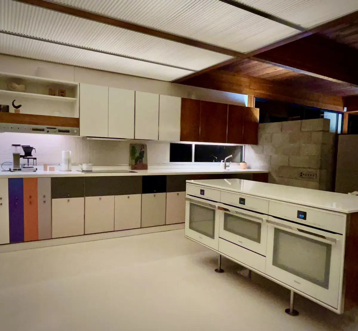 a modern kitchen with white countertops, white cabinets, and a white floor, featuring a large white island with three…