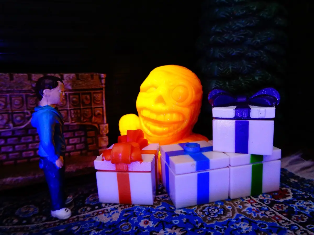 A small figurine of a boy in a blue hoodie stands facing a large, glowing yellow skull with a wide grin, surrounded by…