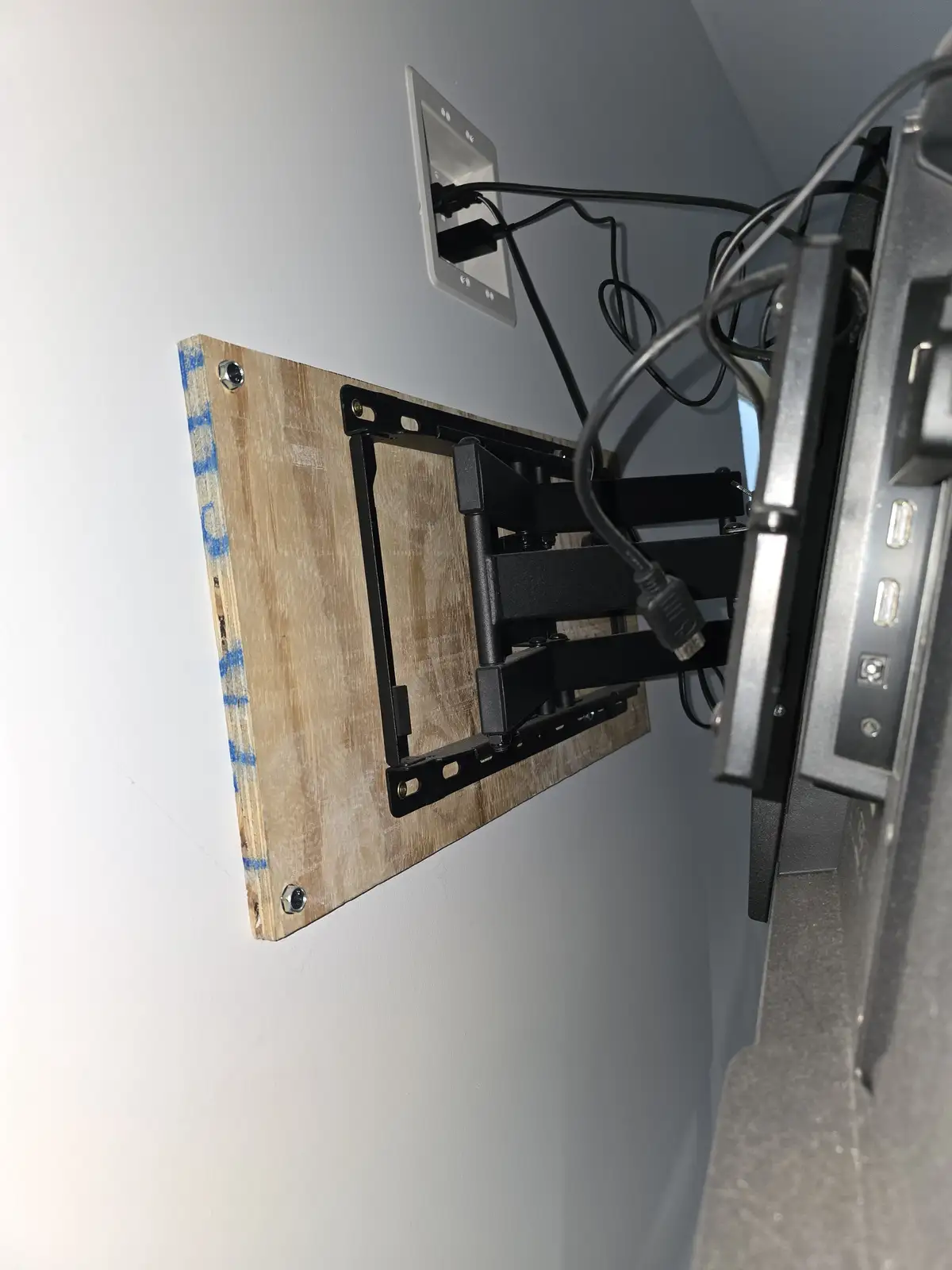 A close-up shot shows a TV wall mount attached to a plain wall, but instead of being mounted directly to drywall, it's…