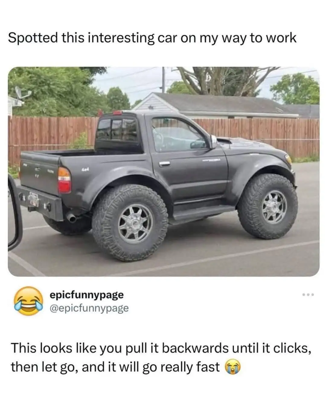 A dark gray pickup truck with extremely oversized, knobby tires and a lifted suspension is parked in a lot. The overlaid…