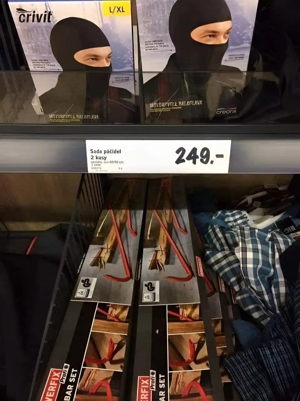 A store shelf displays motorcycle balaclava packaging with models wearing black face coverings above a price tag reading…
