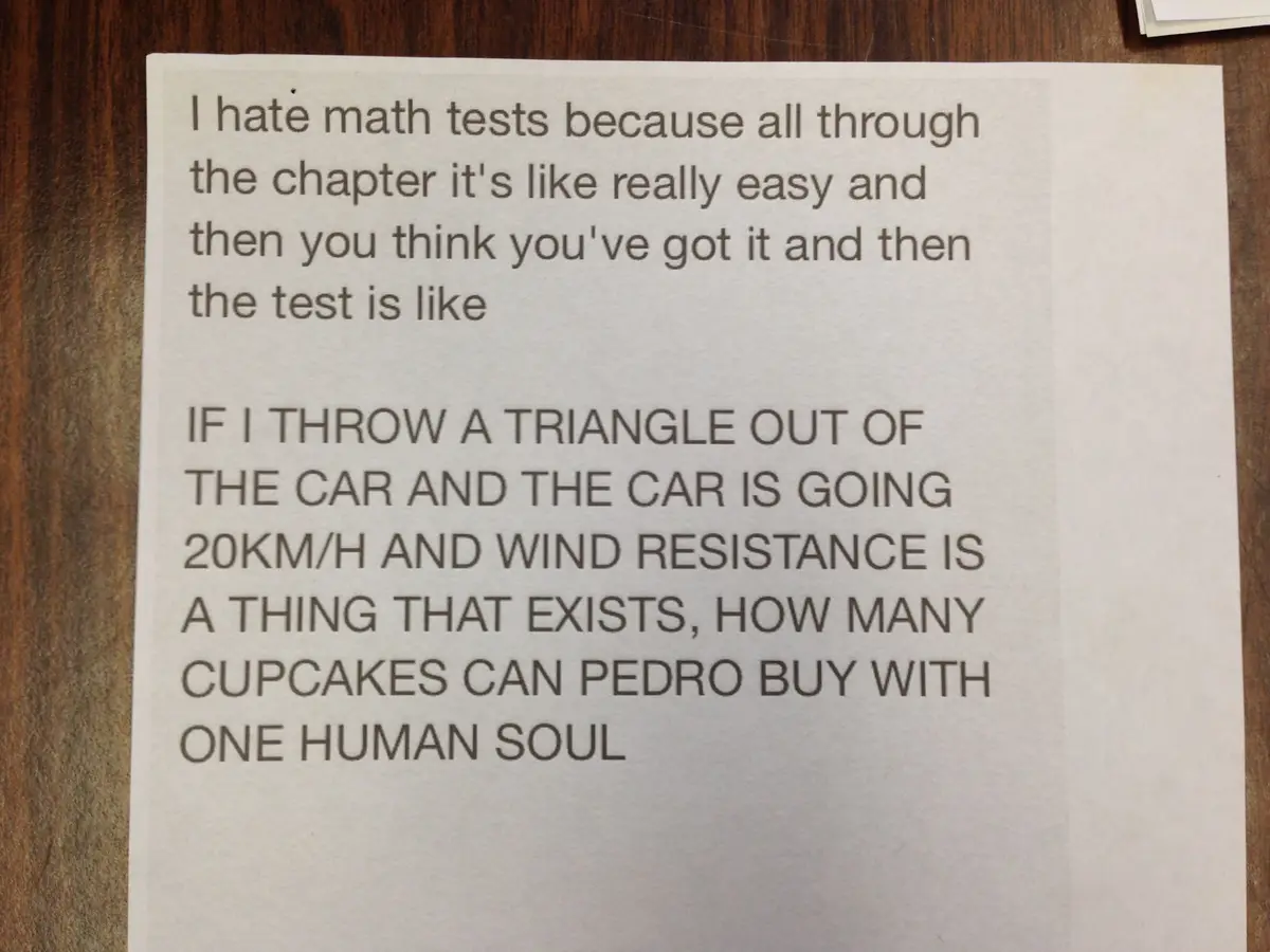 A printed note on white paper rests on a wooden surface. The text describes the frustration of math tests, contrasting easy…