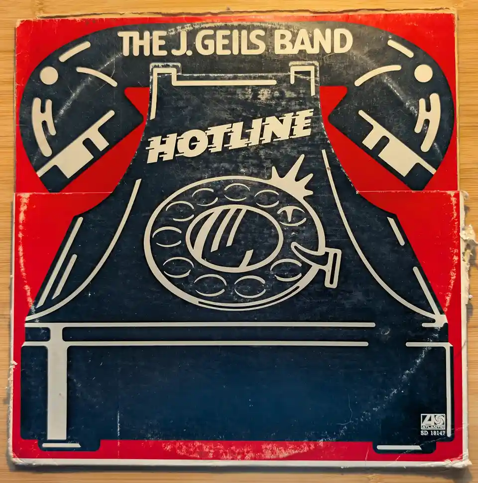 A vintage, worn record sleeve for The J. Geils Band's album 'Hotline' features a stylized graphic of a rotary telephone with…