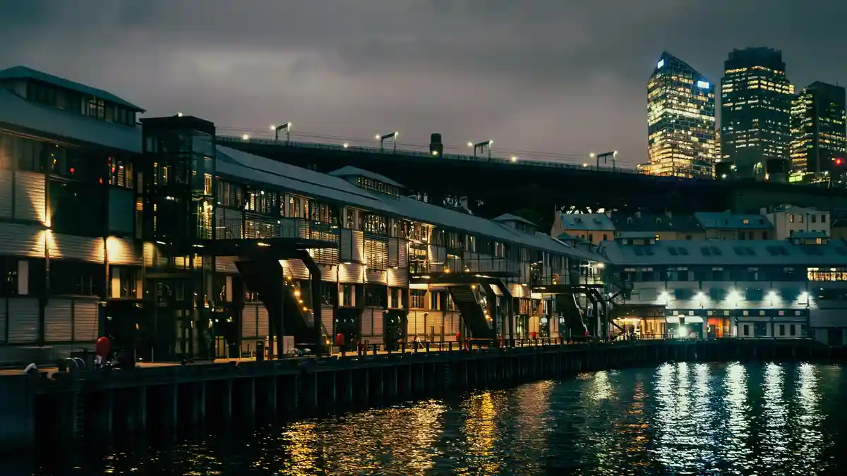 A nighttime city waterfront scene with illuminated buildings and a bridge, with the overlaid text 'i'm not lazy, i'm in…