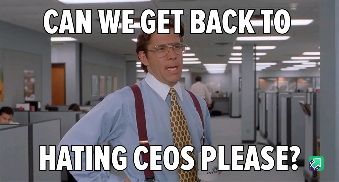 A man in a light blue shirt, patterned tie, and red suspenders stands in an office with cubicles, looking earnestly at the…