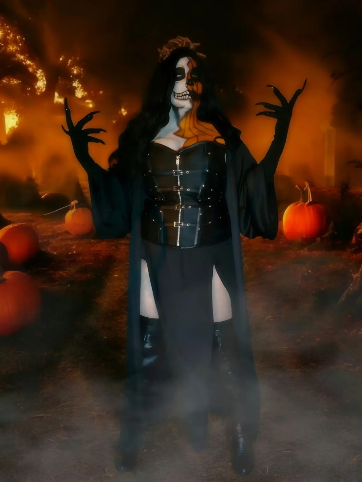 A person in a Halloween costume stands in a spooky, pumpkin-filled field with an orange-hued, smoky background. They wear a…