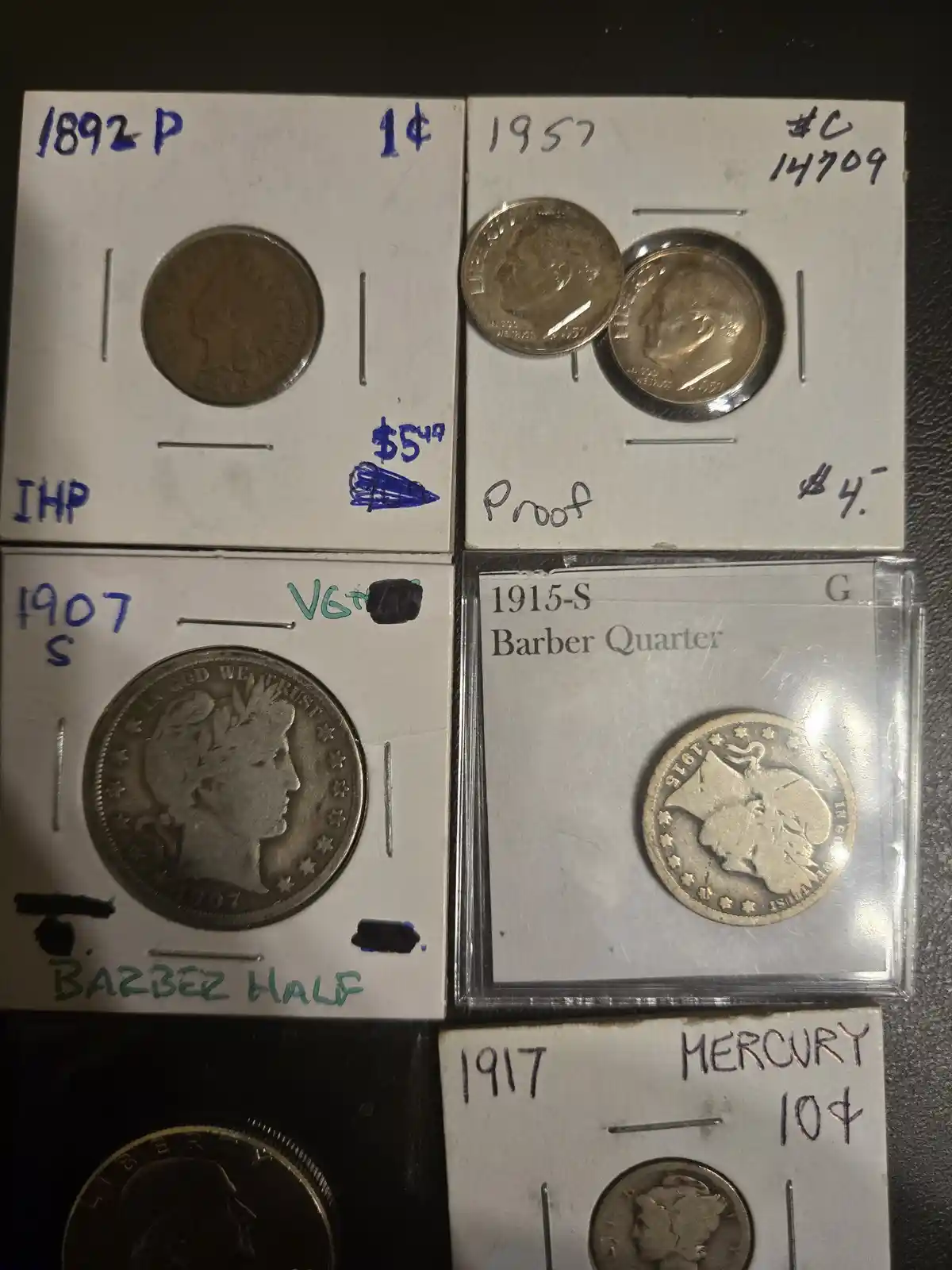 A collection of five U.S. coins displayed in protective holders with handwritten labels indicating their year, denomination…