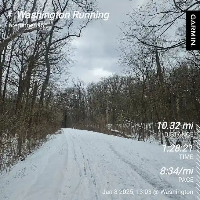 A snowy trail through bare trees under an overcast sky, overlaid with a Garmin Forerunner 955 running GPS screenshot showing…