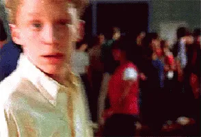 A six-panel image sequence shows a young man with red hair and a white shirt, progressively zooming in on his face as he…