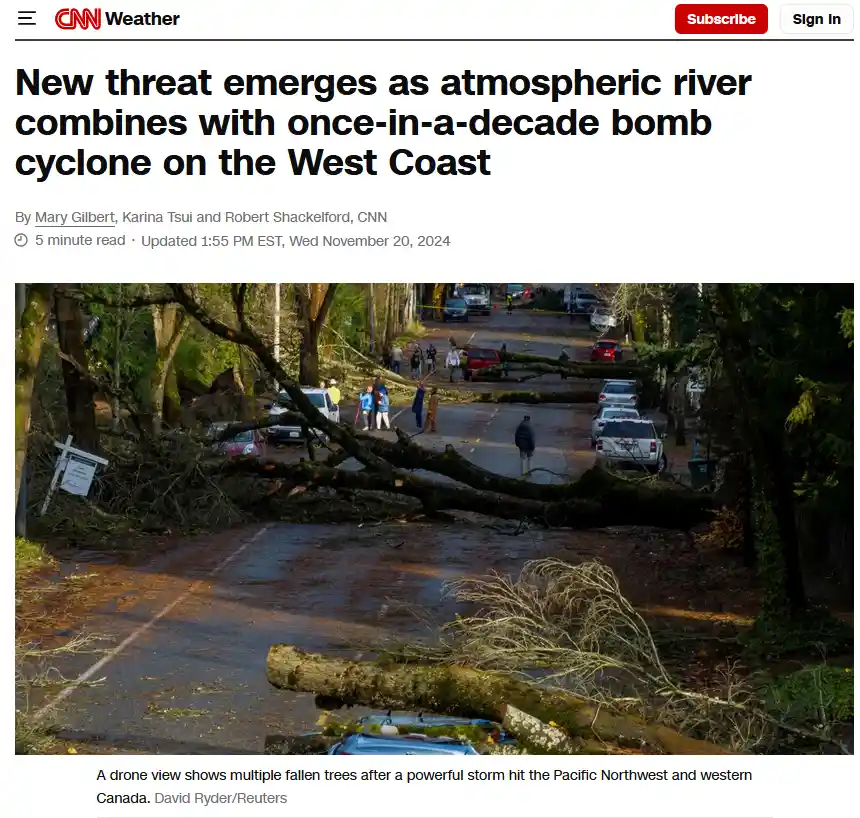 A CNN Weather article screenshot shows a street blocked by fallen trees after a storm, with people walking around and cars…