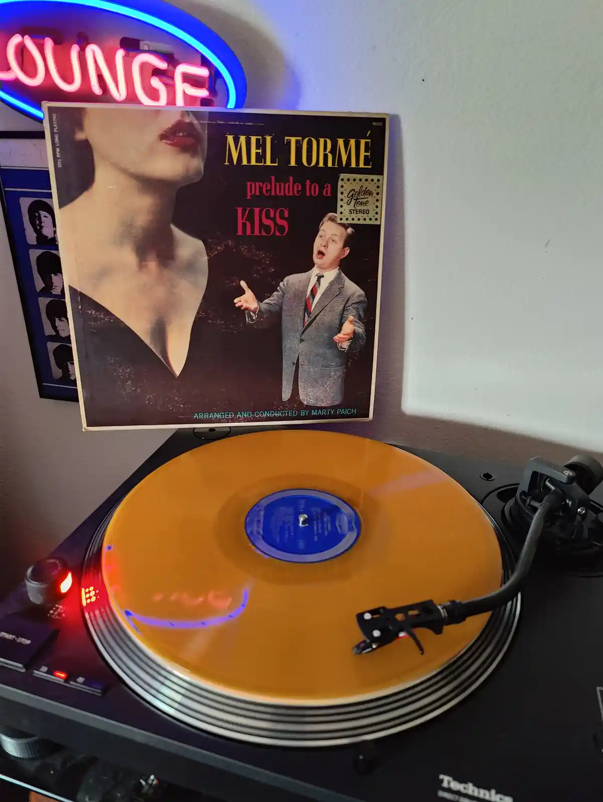 A vintage Mel Tormé album cover for 'Prelude to a Kiss' is propped up against a wall above a modern Technics turntable…