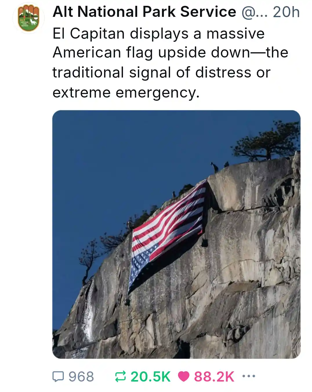 A large American flag is visibly hung upside down on the sheer granite face of El Capitan in Yosemite National Park, with a…