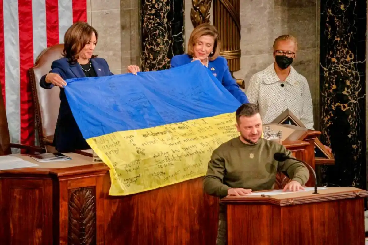 A photo shows Ukrainian President Volodymyr Zelenskyy seated at a podium in a formal setting, likely the U.S. Capitol, while…