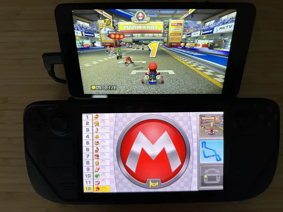 A Nintendo 3DS console displays Mario Kart gameplay on its top screen, showing Mario in first place at the start of a race…