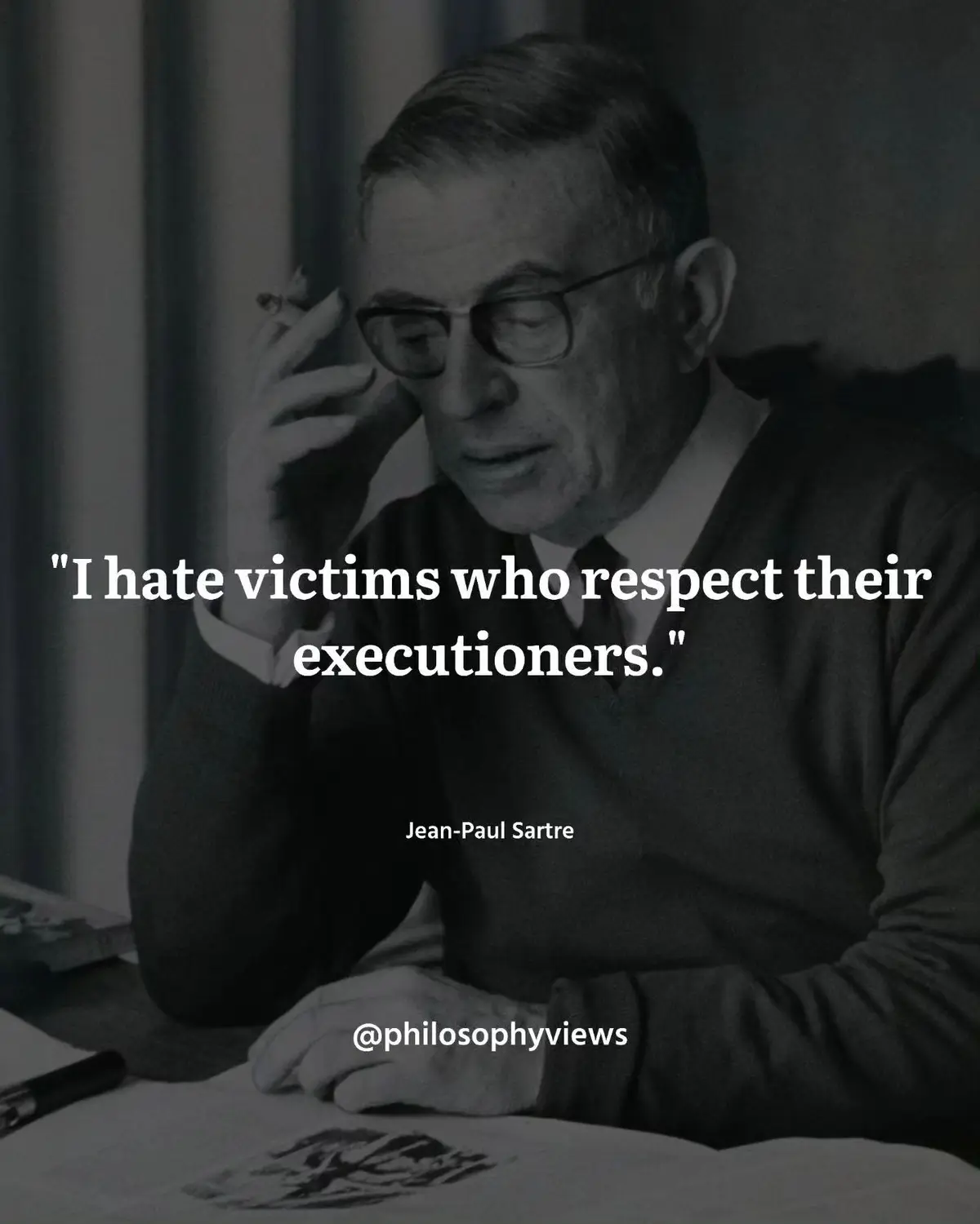A black-and-white photo of philosopher Jean-Paul Sartre, wearing glasses and a sweater, holding a cigarette while seated at…