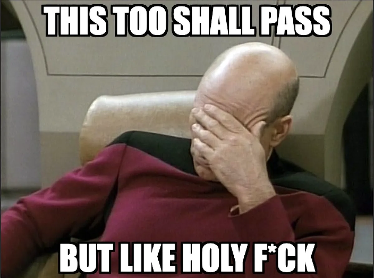 A bald man in a red Starfleet uniform sits in a chair, covering his face with his hand in a gesture of exasperation or…