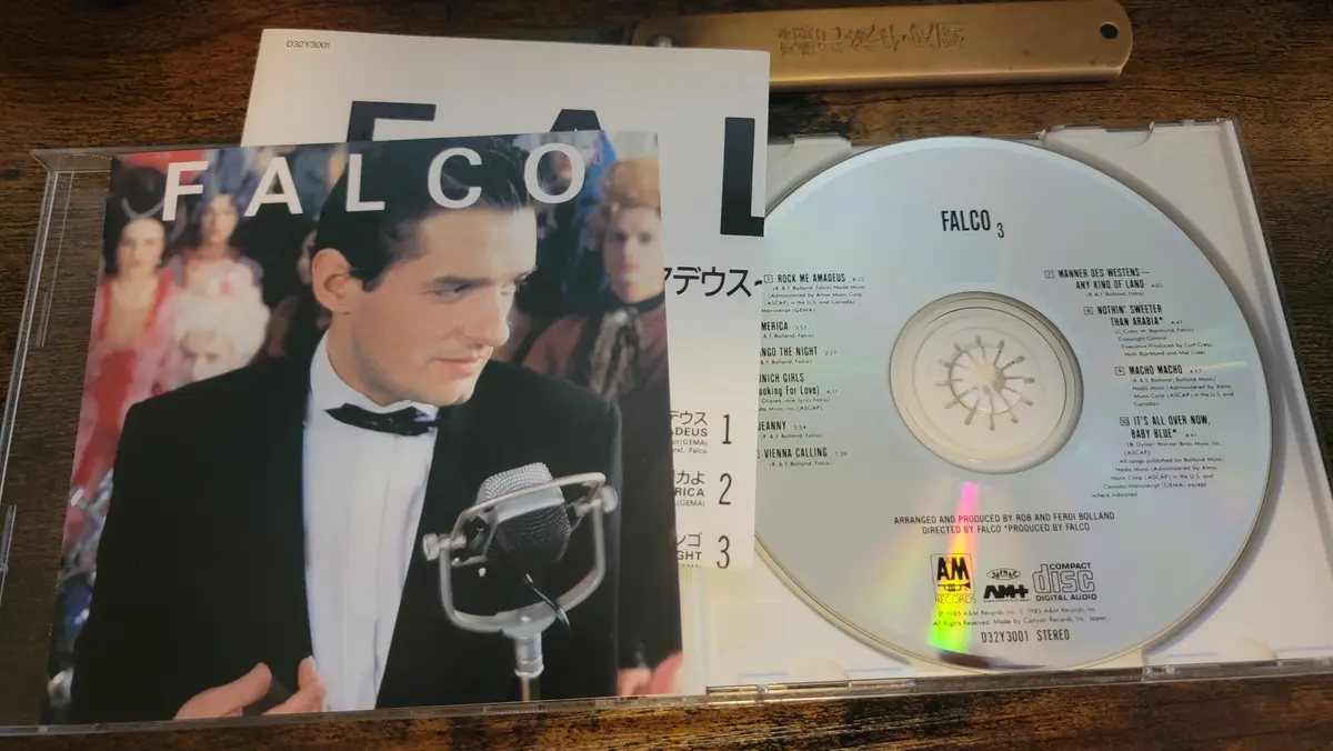 A photo of the physical CD release of Falco's album 'Falco 3', showing the open jewel case with the album cover featuring…