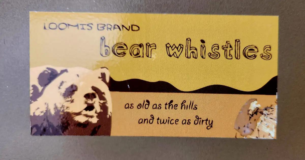 A yellow rectangular label with a stylized bear illustration on the left and a mountain range silhouette. The text reads…