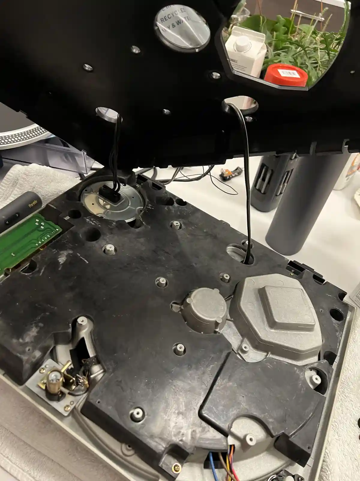 A close-up photo shows the internal components of a disassembled treadmill, with its black plastic casing open to reveal…