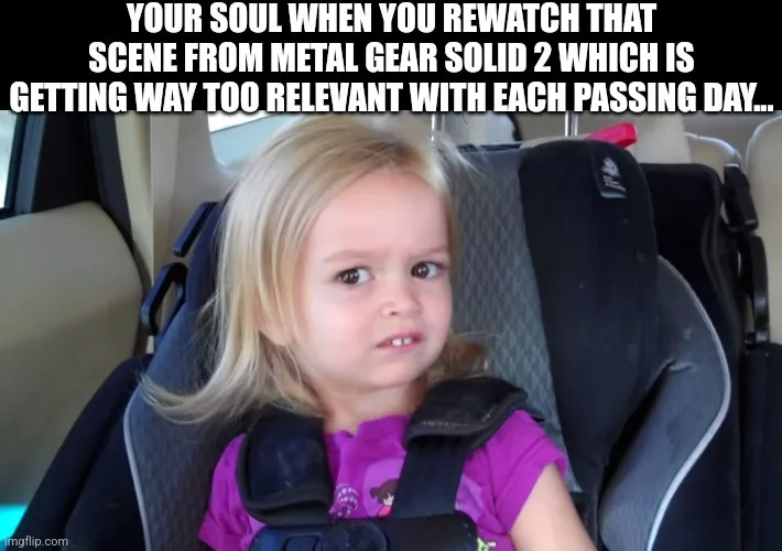 A young girl with blonde hair sits in a car seat, looking intensely at the camera with a skeptical, slightly annoyed…
