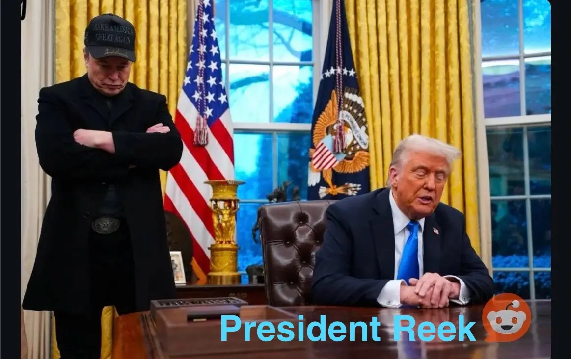A man wearing a 'Make America Great Again' cap and a black coat stands with arms crossed in the Oval Office, looking down…