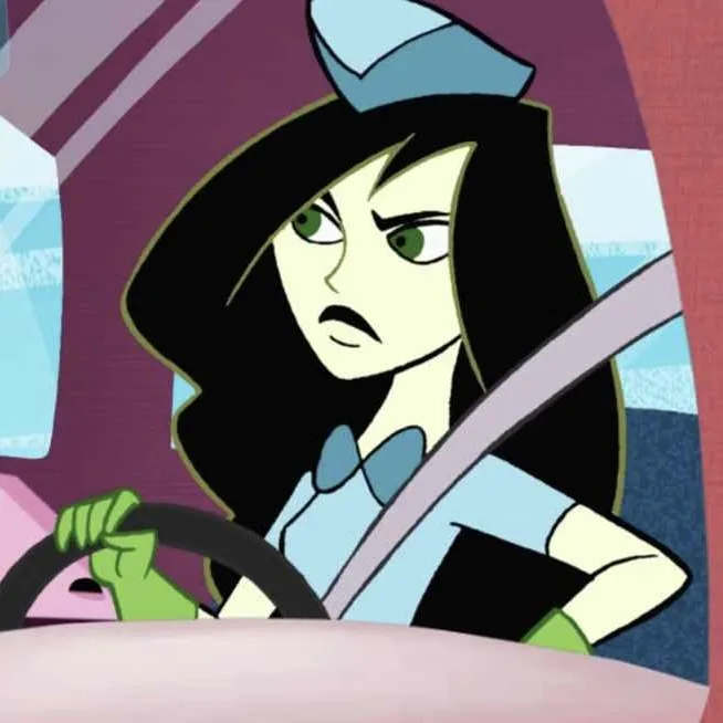 An animated female character with black hair and green eyes, wearing a blue hat and bowtie, sits in a car with a furious…