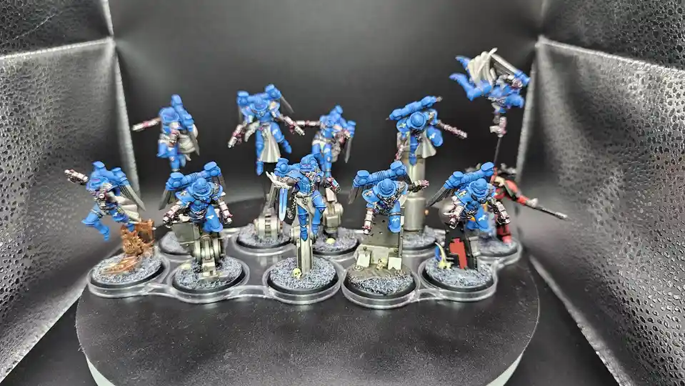 A collection of blue-painted miniature figurines, likely from Warhammer 40,000, are displayed on clear plastic bases…