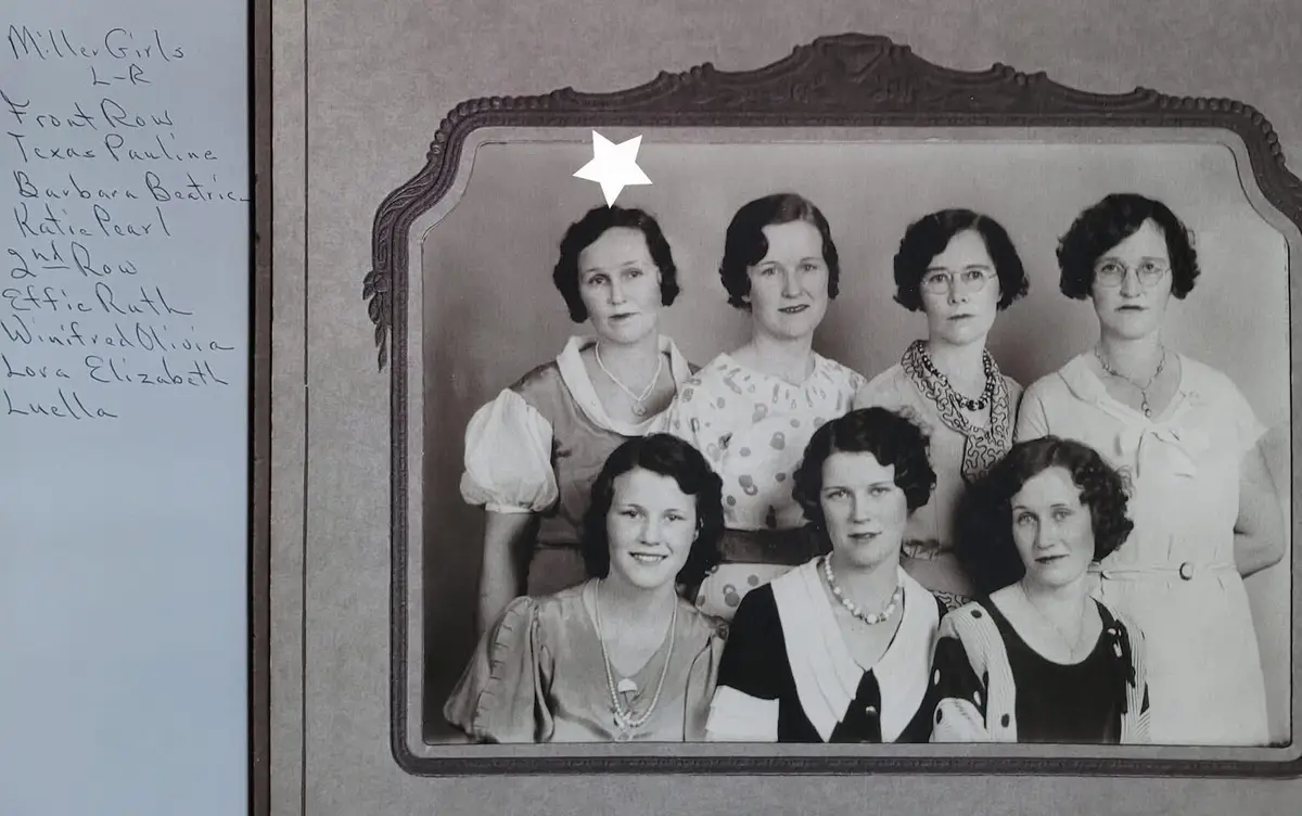 A vintage black-and-white family portrait shows seven women in two rows, dressed in 1930s-style clothing with pearls and…