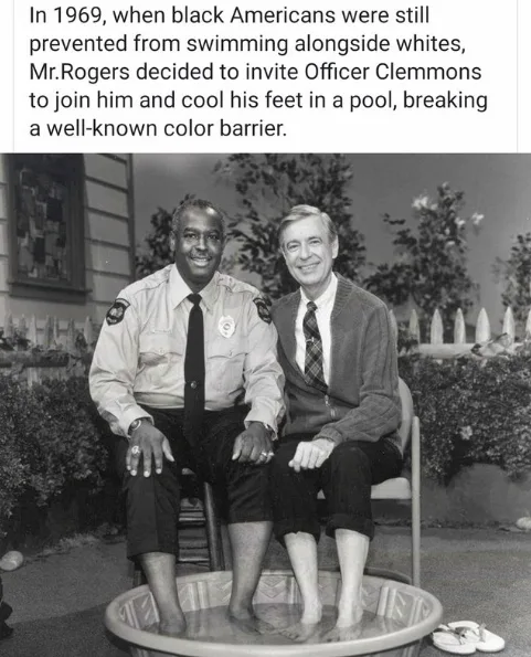 A black-and-white photo shows two men sitting side-by-side on chairs with their feet in a small, shallow pool. The man on…