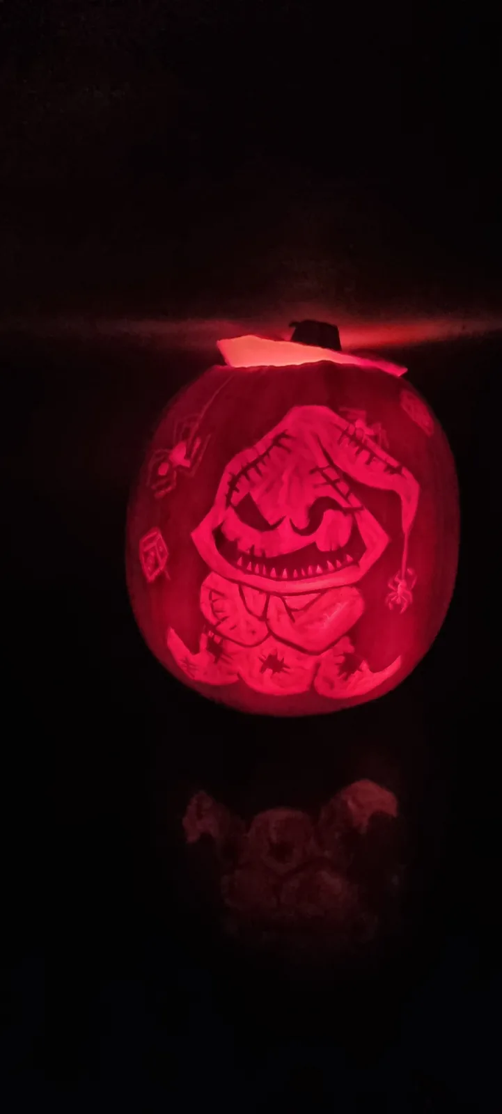 A carved pumpkin illuminated from within by a red light, displaying a detailed design of the character Jack Skellington from…