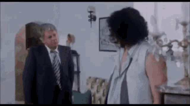 A six-panel sequence from a movie shows a man in a suit and a woman with curly hair interacting. Initially, they stand…