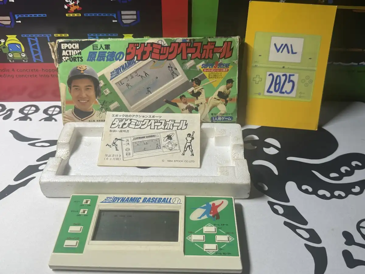 A vintage 1984 Epoch 'Dynamic Baseball' handheld game sits in its original box and manual, next to a yellow box labeled 'VAL…
