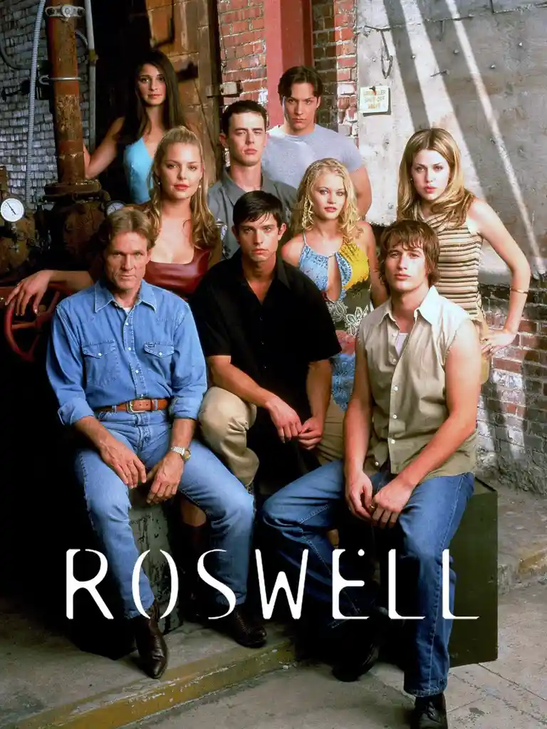 The image is a promotional poster for the TV show 'Roswell,' featuring the main cast posing in front of a brick wall and…
