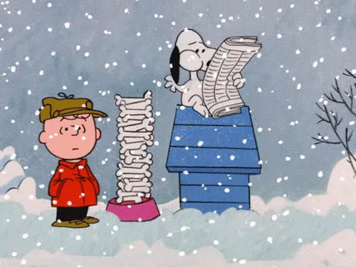 A snowy scene from the Peanuts comic strip shows Charlie Brown standing beside Snoopy's blue doghouse, which has a large…