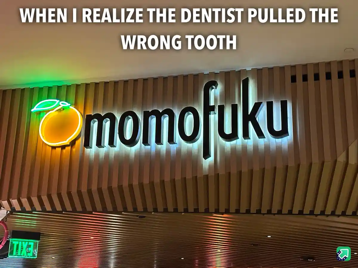 The image shows a brightly lit 'momofuku' restaurant sign with a neon orange logo on a wooden slat wall. White text overlaid…