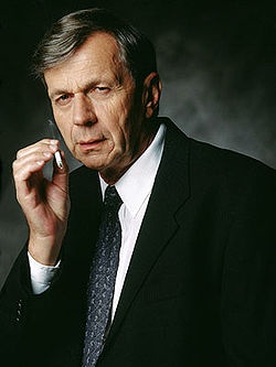 A man in a dark suit and tie holds a cigarette near his mouth, looking sternly at the camera. The overlaid text reads: 'I'm…