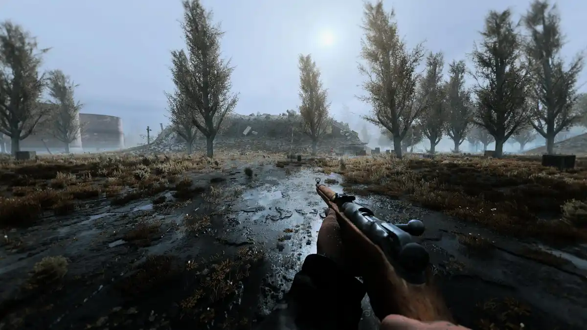 A first-person view from a video game shows a player holding a rifle in a bleak, muddy, post-apocalyptic landscape with…