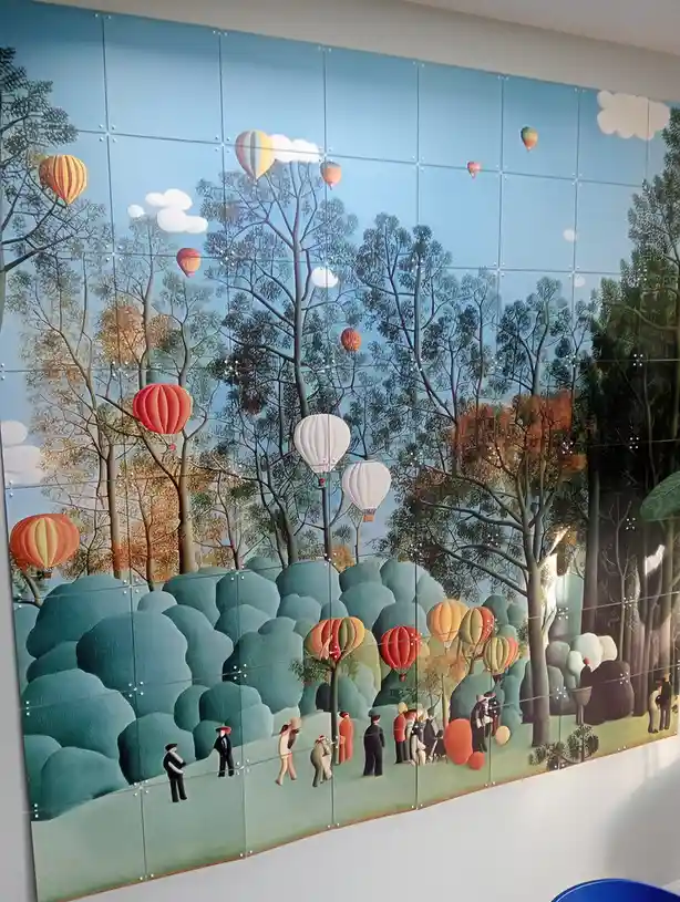 A colorful mural depicts a whimsical forest scene with numerous hot air balloons floating among and seemingly growing from…