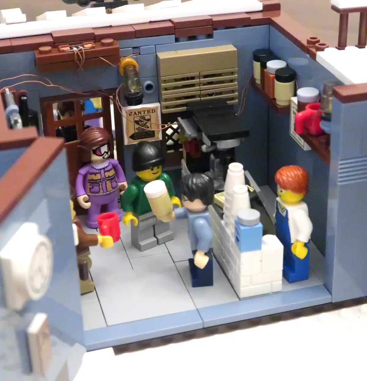 A detailed Lego diorama of a Western-style saloon with several minifigures: a cowboy with a wanted poster, a man in a green…