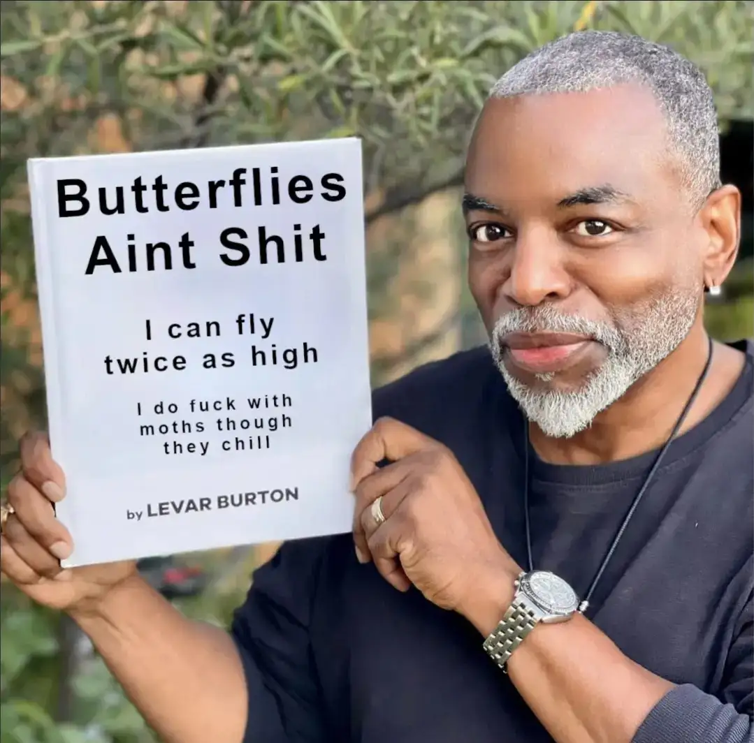 A man with gray hair and a beard holds up a white book with black text that reads 'Butterflies Aint Shit', followed by 'I…