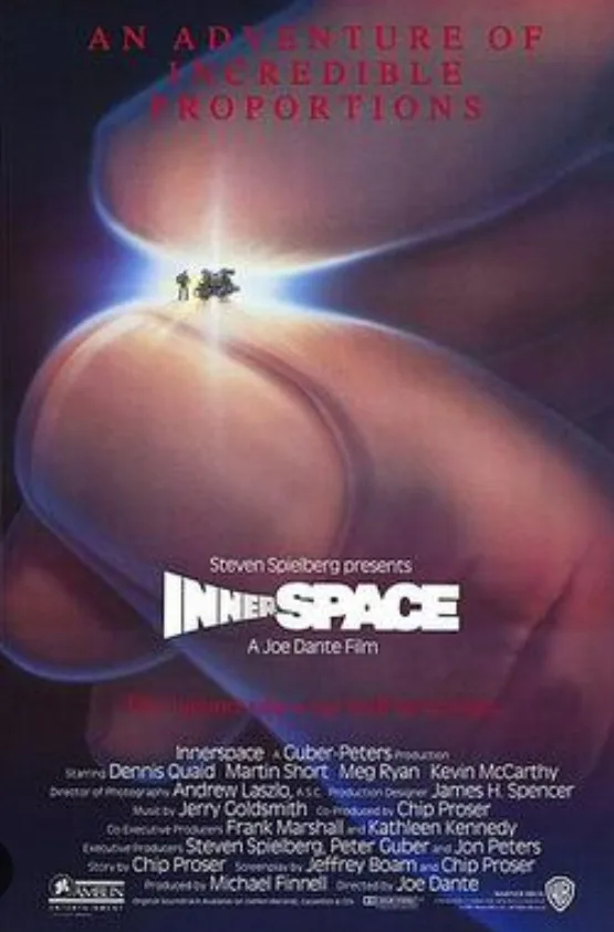 The image is a movie poster for 'Innerspace,' showing two tiny figures standing on the tip of a giant human finger, with the…