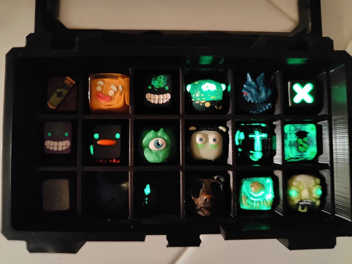 A black plastic tray holds 15 small, colorful, glowing figurines of various cartoonish monsters and characters, arranged in…