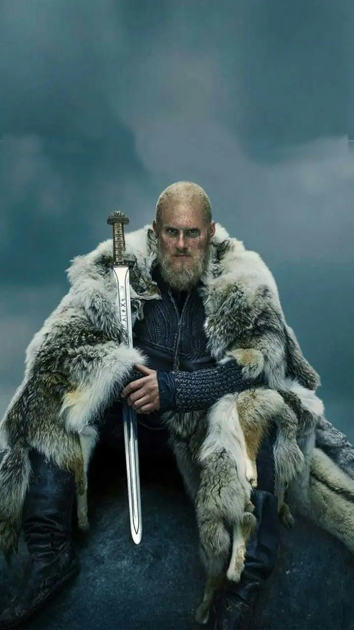 A bald, bearded man in a thick fur-lined coat sits on a stone throne, holding a sword upright. The background is a misty…