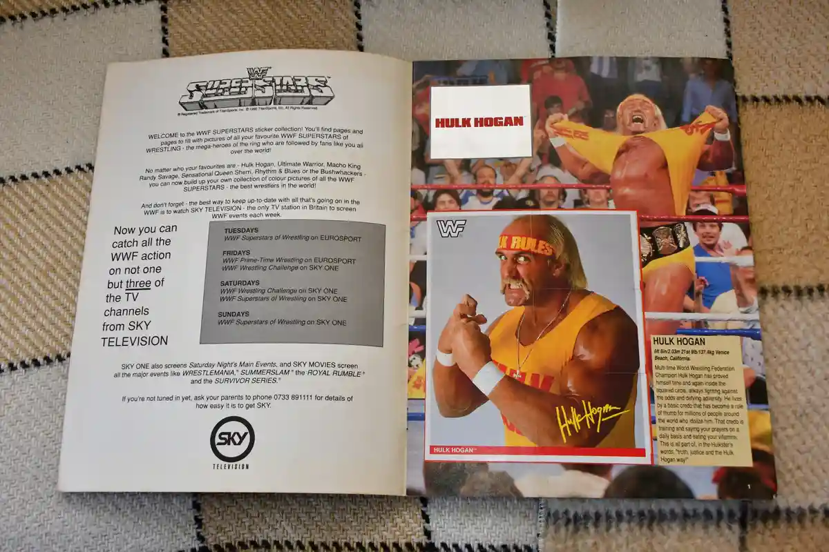 An open 1990 WWF Superstars sticker collection booklet lies on a woven rug. The left page advertises Sky Television's WWF…