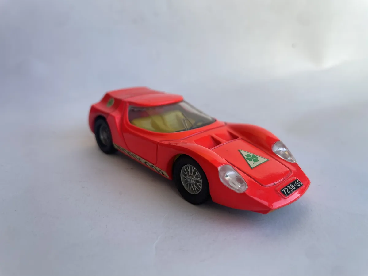 A red toy sports car with a green four-leaf clover emblem on the hood and a license plate reading '7238-GE' is photographed…