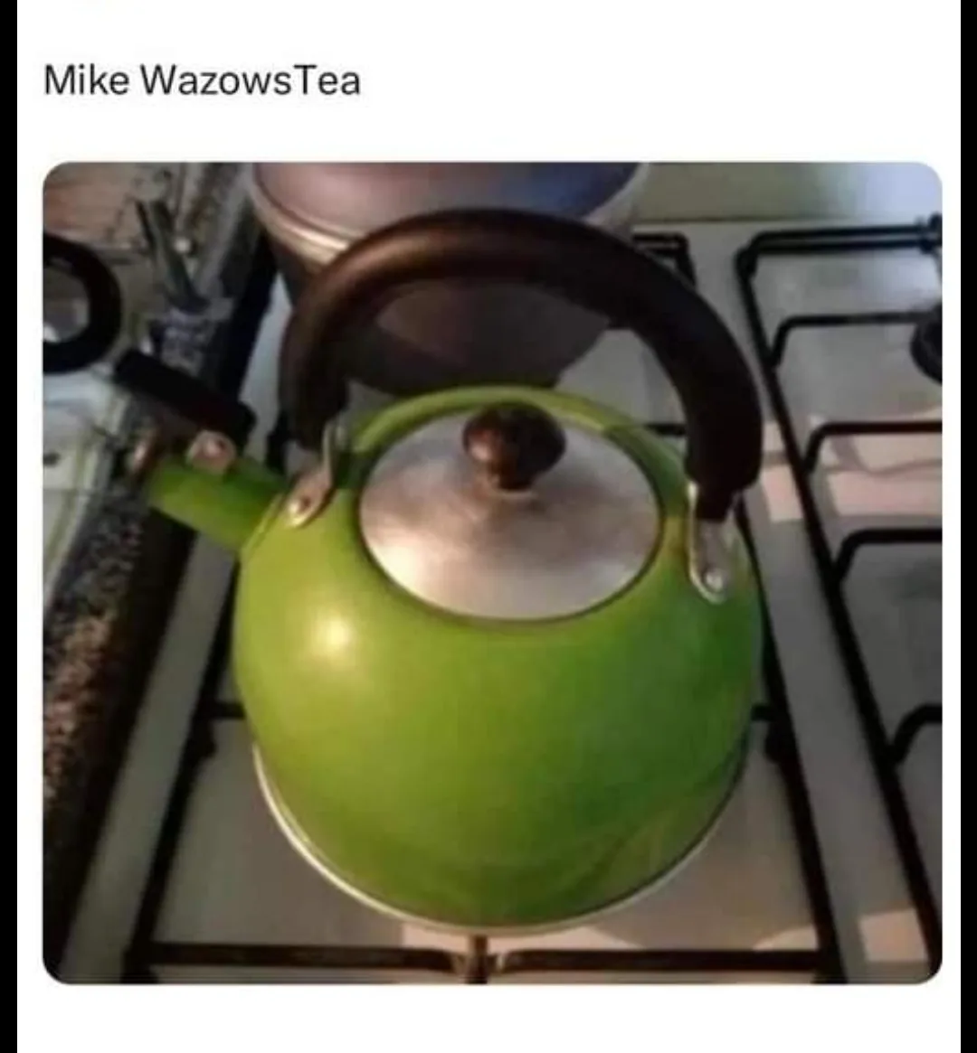 A bright green kettle with a silver lid and black handle sits on a gas stove burner. The image has the text 'Mike WazowsTea'…